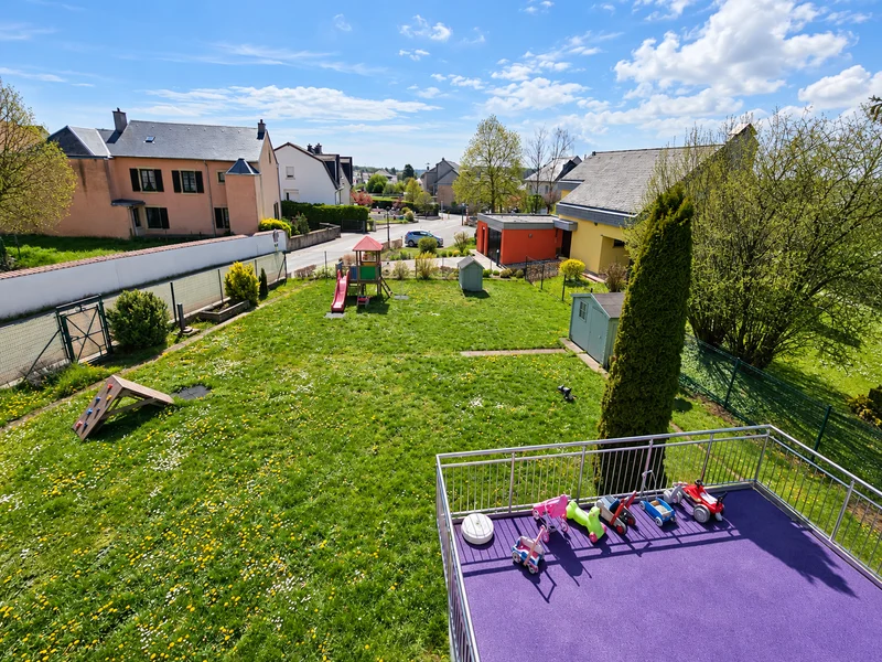 Vue en hauteur du jardin de la crèche, avec les jeux et la terrasse violette